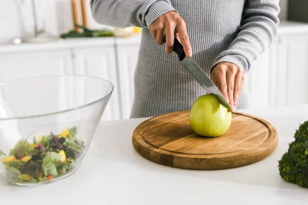 Cropped view of girl holding knife near green whole apple — Stock Photo