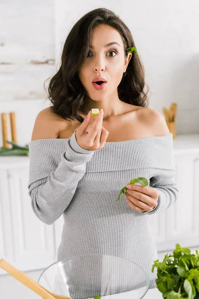 Здивована дівчина тримає свіже яблуко біля зеленої м'яти — стокове фото