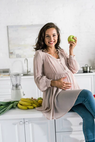 Happy pregnant woman holding apple near bananas — Stock Photo