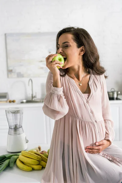 Feliz embarazada comer manzana cerca de plátanos - foto de stock