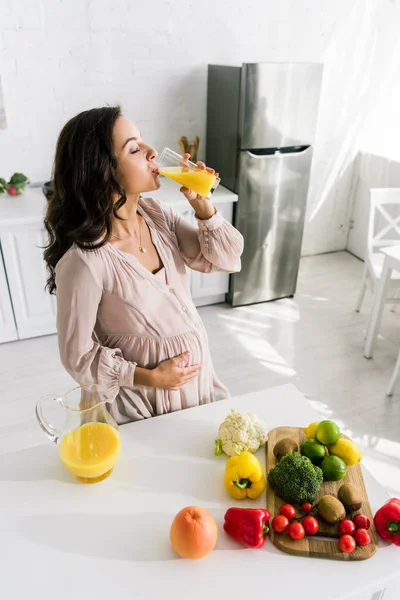 Attraktive schwangere Frau trinkt frischen Orangensaft — Stockfoto