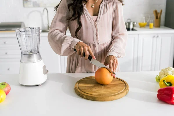 Visão cortada da mulher grávida cortando toranja — Fotografia de Stock