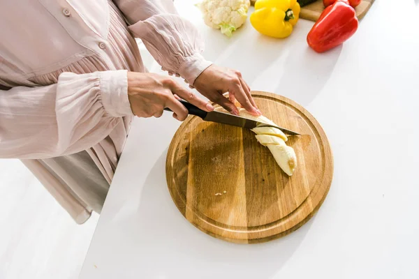 Vista ritagliata della donna incinta taglio banana sul tagliere — Foto stock
