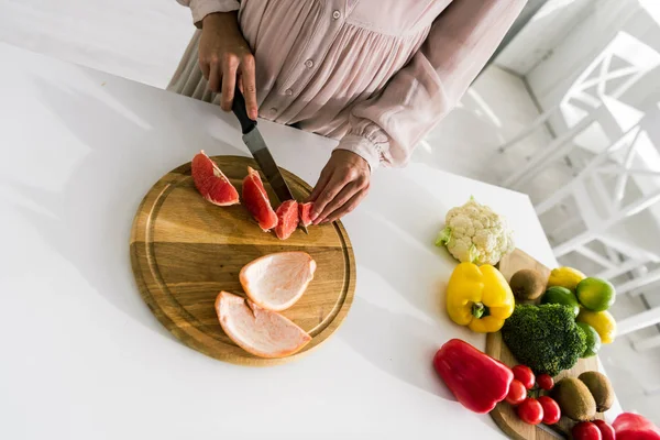 Blick aus der Vogelperspektive auf junge Schwangere, die Grapefruit schneidet — Stockfoto