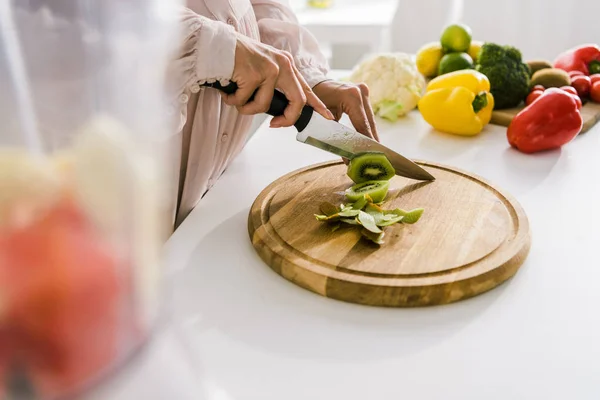 Selective focus of pregnant woman cutting kiwi on chopping board — Stock Photo