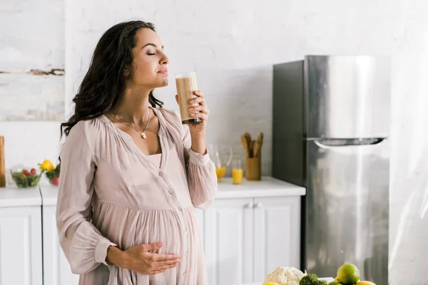 Happy pregnant woman holding glass with tasty smoothie — Stock Photo