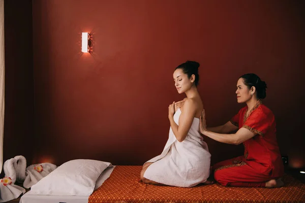 Asiatico massaggiatore wrapping con asciugamano attraente donna in spa salone — Foto stock