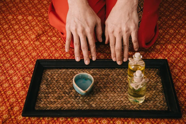 Cropped view of masseur with fragrance oils in bottles and bowl — Stock Photo