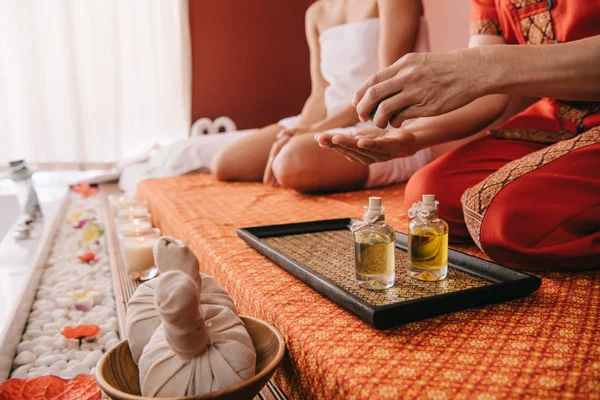 Geschnittene Ansicht des Masseurs, der Parfümöl auf die Hand gießt — Stockfoto