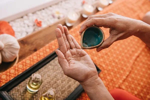 Cropped view of masseur pouring fragrance oil on hand — Stock Photo