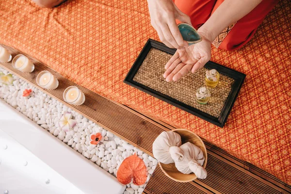 Cropped view of masseur pouring fragrance oil on hand — Stock Photo