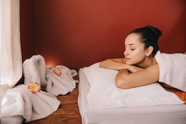 Attractive woman with closed eyes lying on massage mat — Stock Photo