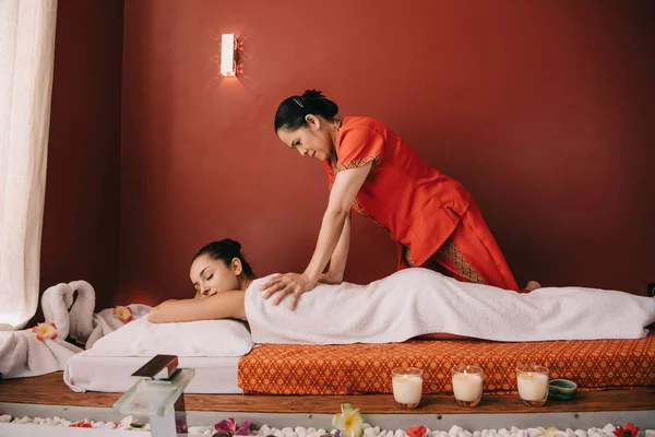 Asiatique masseur faire retour massage à attrayant femme dans spa salon — Photo de stock