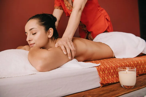 Recortado vista de masajista haciendo masaje de espalda a la mujer en alfombra de masaje - foto de stock