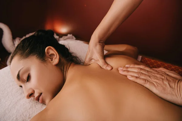 Recortado vista de masajista haciendo masaje de espalda a la mujer en alfombra de masaje - foto de stock