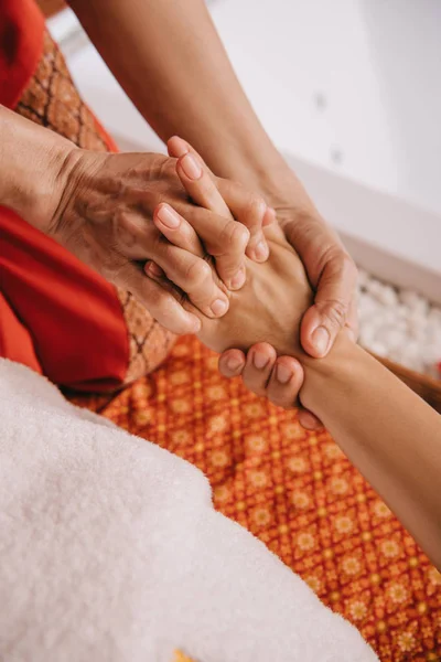 Vista ritagliata del massaggiatore facendo massaggio della mano alla donna nel salone spa — Foto stock