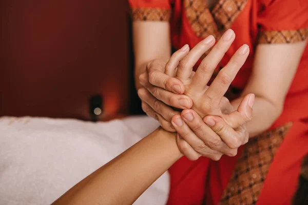 Vista cortada de massagista fazendo massagem de mão para a mulher no salão de spa — Fotografia de Stock