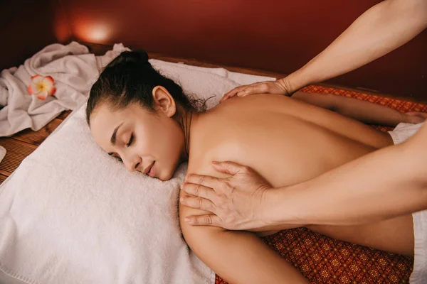 Vue recadrée du masseur faisant massage du dos à la femme sur tapis de massage — Photo de stock