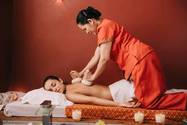Ásia massagista fazendo de volta massagem com ervas bolas para mulher no spa — Fotografia de Stock