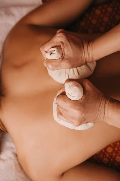 Vue recadrée de masseur faisant massage du dos avec des boules à base de plantes à la femme dans le spa — Photo de stock