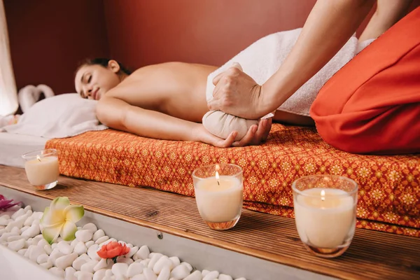 Vue recadrée de masseur faisant massage avec boule à base de plantes à la femme dans le spa — Photo de stock