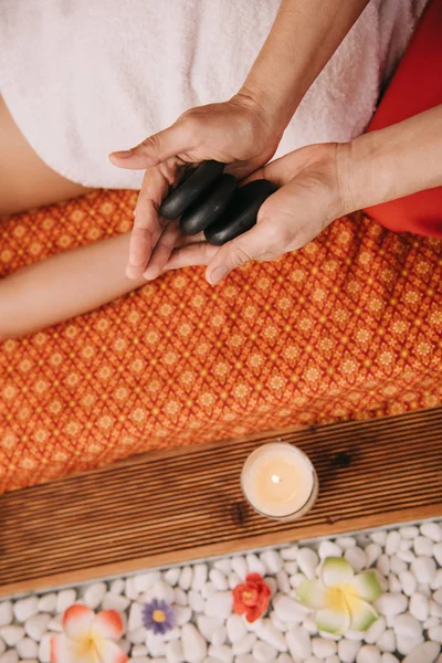 Обрізаний вид масажиста, що тримає гарячі камені для масажу — стокове фото
