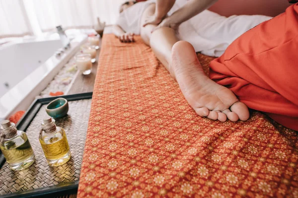 Vista ritagliata del massaggiatore che fa massaggio ai piedi alla donna nel salone spa — Foto stock