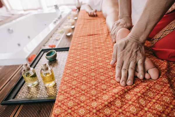 Обрезанный вид массажера, делающего массаж ног женщине в спа-салоне — стоковое фото