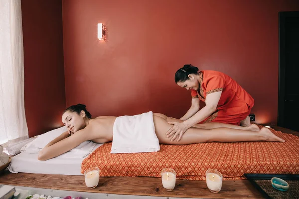 Vue latérale de masseur asiatique faisant massage des pieds à la femme dans le salon de spa — Photo de stock