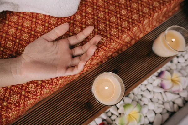Vista ritagliata della donna sdraiata sul tappeto da massaggio nel salone spa — Foto stock