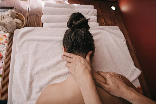 Recortado vista de masajista haciendo masaje de cuello a mujer en salón de spa - foto de stock