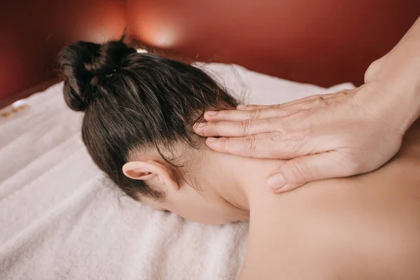 Vue recadrée du masseur faisant massage du cou à la femme dans le salon de spa — Photo de stock