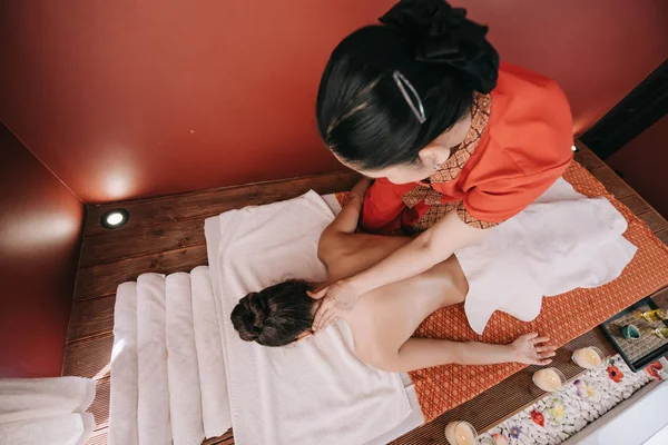 Visão de alto ângulo do massagista fazendo massagem no pescoço para a mulher no salão de spa — Fotografia de Stock