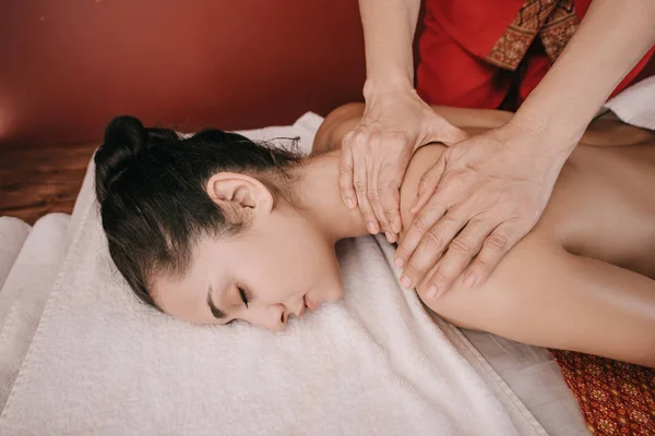 Recortado vista de masajista haciendo masaje de cuello a mujer en salón de spa - foto de stock