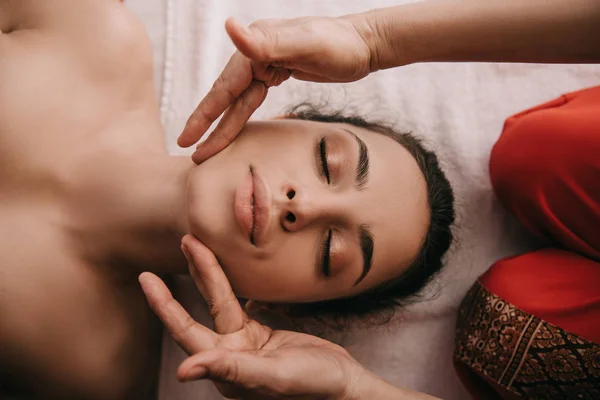 Обрезанный вид массажера, делающего массаж лица женщине в спа-салоне — стоковое фото