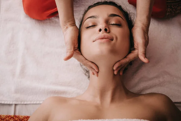 Vista ritagliata del massaggiatore facendo massaggio viso alla donna nel salone spa — Foto stock