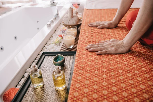 Vista recortada de masajista sentado en alfombra de masaje en el spa - foto de stock