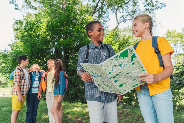 Selective focus of african american boy smiling with friend while holding map — Stock Photo