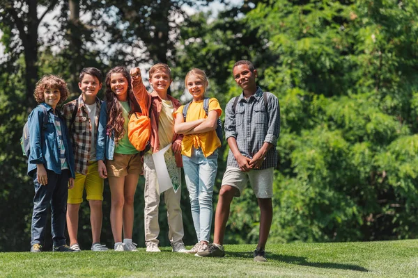 Fröhliche multikulturelle Kinder stehen auf grünem Gras — Stockfoto