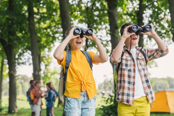 Selective focus of happy kids looking through binoculars — Stock Photo