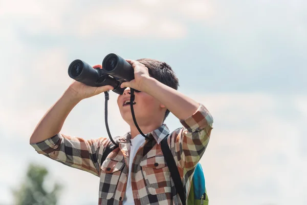 Glückliches Kind blickt durch Ferngläser gegen blauen Himmel — Stockfoto