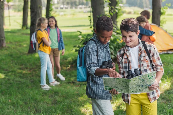 Enfoque selectivo de niño afroamericano mirando el mapa cerca de amigo - foto de stock