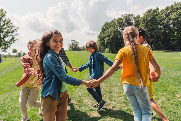 Selective focus of happy multicultural kids holding hands — Stock Photo