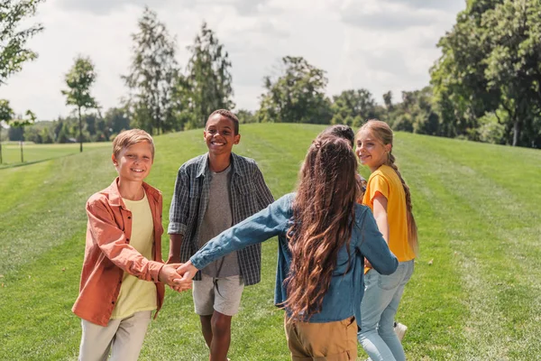 Щасливий мультикультурному діти тримають руки і посміхається в парку — стокове фото