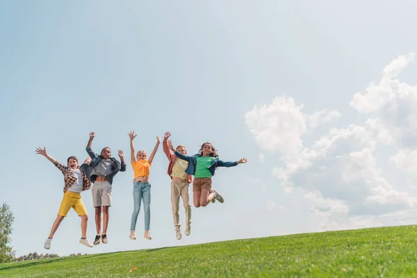 Щасливий мультикультурному діти стрибки і жестами проти синього неба — стокове фото