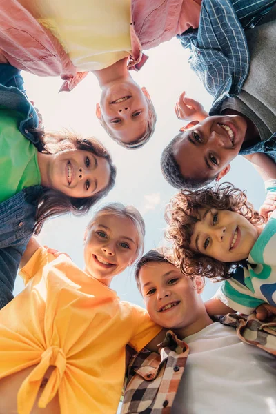 Vista dal basso di allegri bambini multiculturali guardando la fotocamera — Foto stock