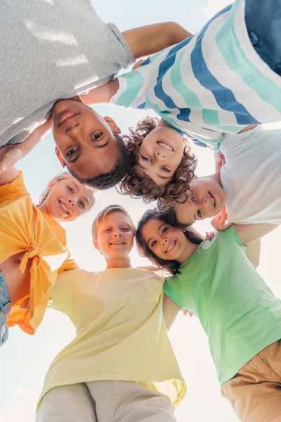 Vue du bas des enfants multiculturels positifs regardant la caméra — Photo de stock