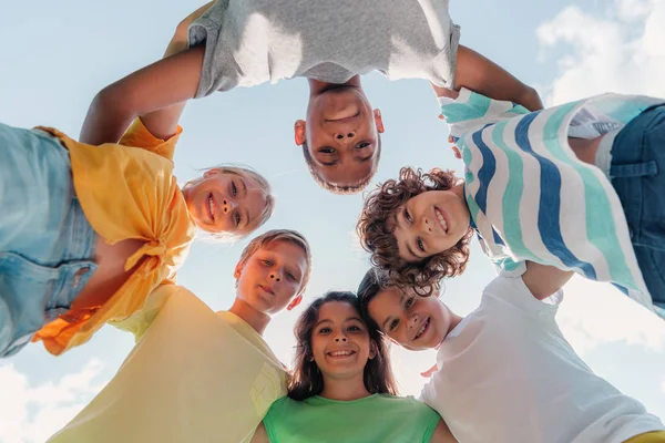 Blick von unten auf positive multikulturelle Kinder, die in die Kamera schauen — Stockfoto