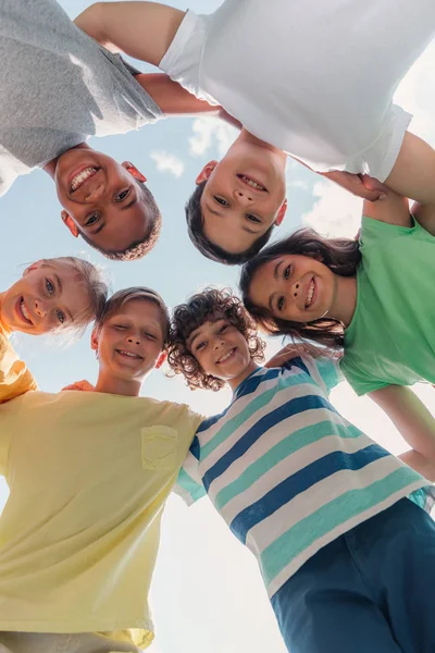 Blick von unten auf lächelnde multikulturelle Kinder, die in die Kamera schauen — Stockfoto