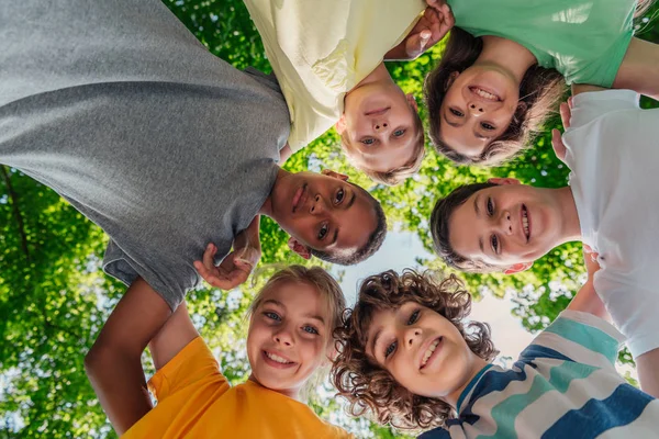 Vue du bas des enfants multiculturels heureux regardant la caméra — Photo de stock